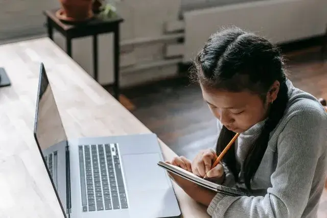 Jovem estudando com notebook em uma biblioteca.